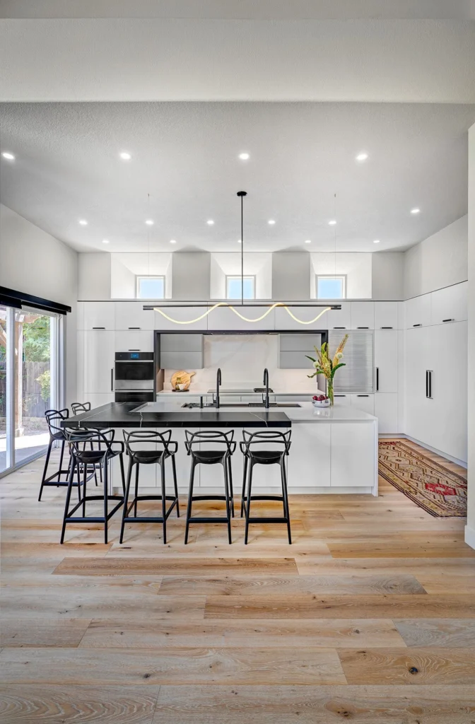 Blanc and Noir kitchen remodel featuring sculptural LED pendant lighting and layered recessed lighting over work zones in Sacramento, CA by Tenax Construction