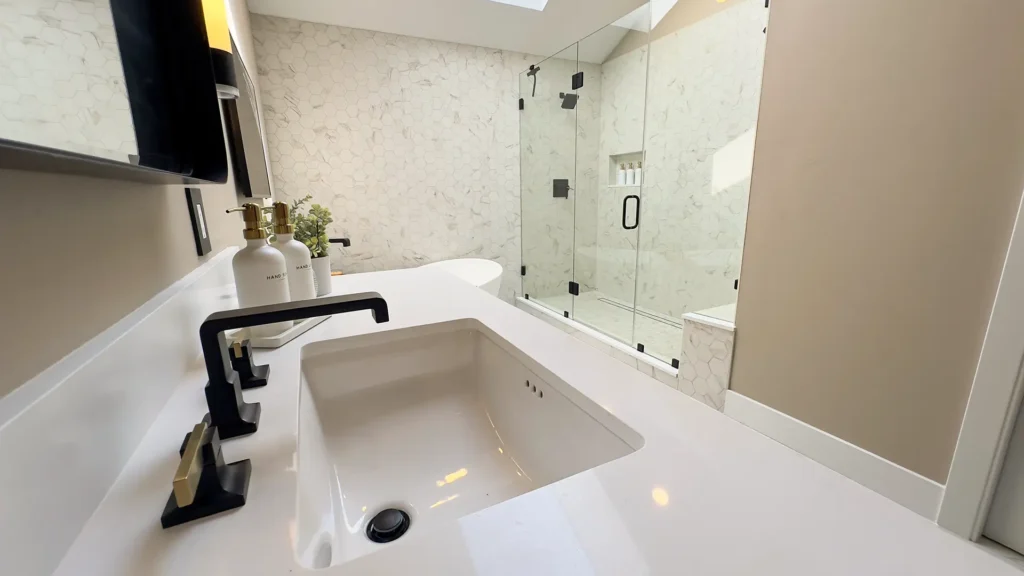 Luxury primary bathroom remodel featuring freestanding bathtub with sleek waterfall faucet in Gold River, CA by Tenax Construction