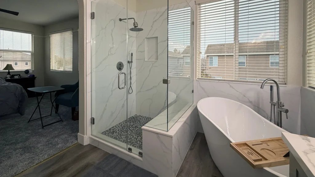 Spa-like master bathroom remodel featuring waterfall tub filler and marble wall tile up to window sill height in Elk Grove, CA by Tenax Construction