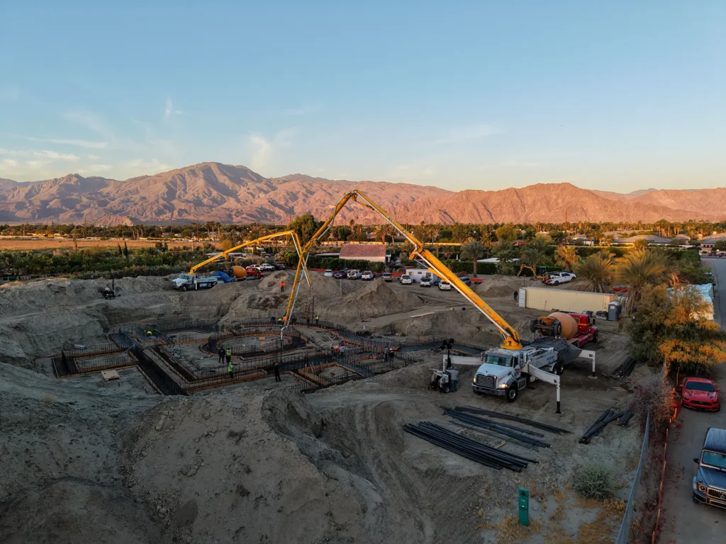 Luxury ICF custom home construction featuring concrete mixer trucks staged for continuous foundation pour in Indio, CA by Tenax Construction
